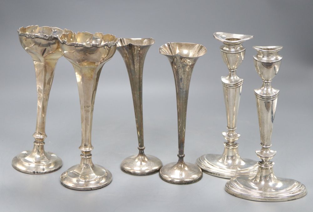 A pair of George V silver candlesticks, (lacking one sconce) 20cm, a pair of specimen vases, 19cm and a larger pair of specimen vases,